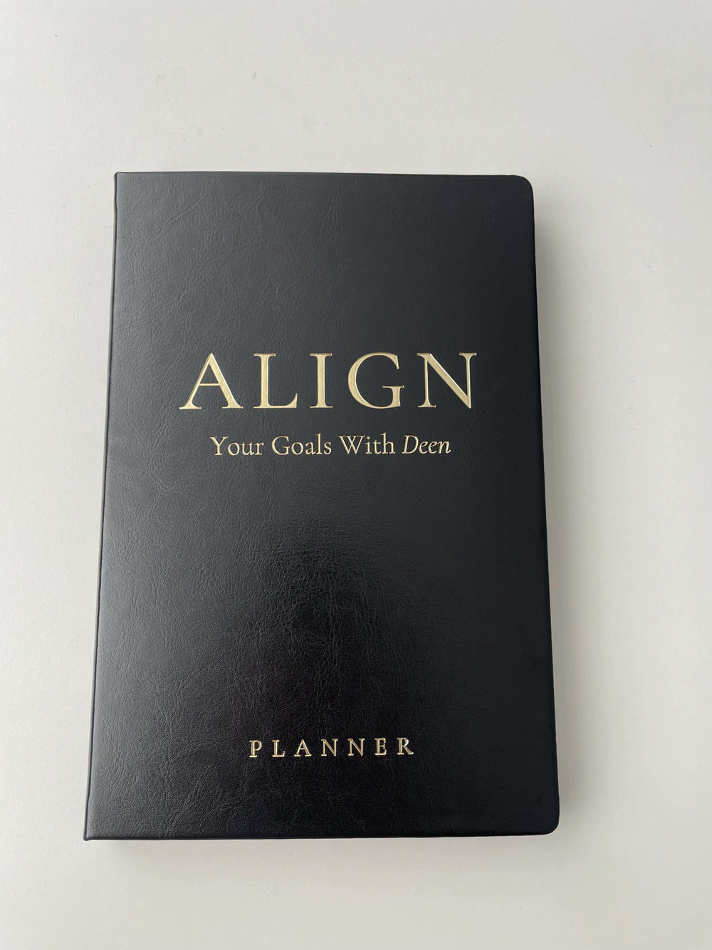 Black Luxe Ebony planner with gold embossed text, rectangular shape, and smooth leather-like cover from AlignbyNura.